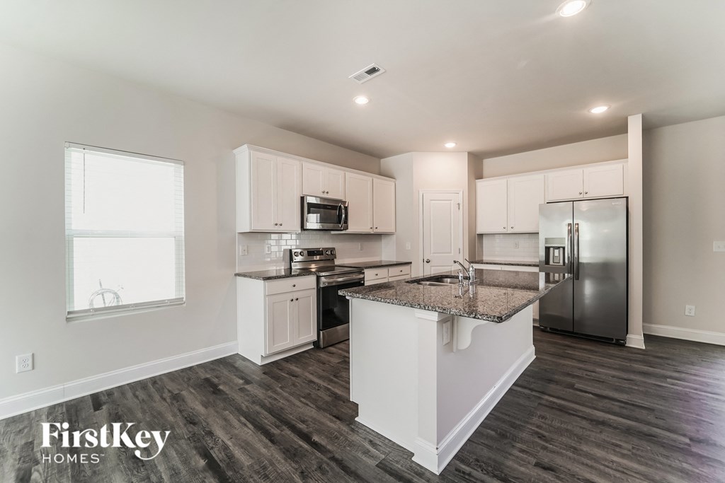 a white kitchen with stainless steel appliances and a granite counter top