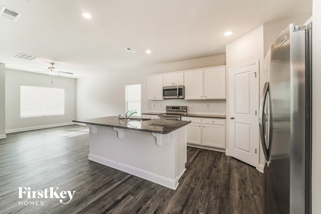 a white kitchen with stainless steel appliances and a marble counter top