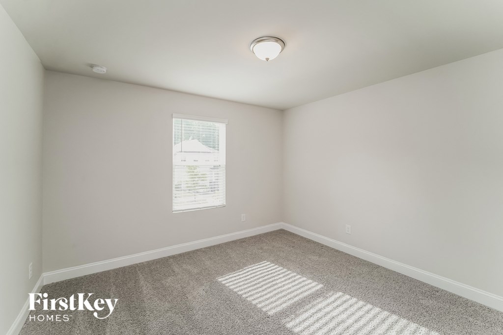 a bedroom with white walls and carpet and a window