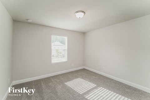 a bedroom with white walls and carpet and a window