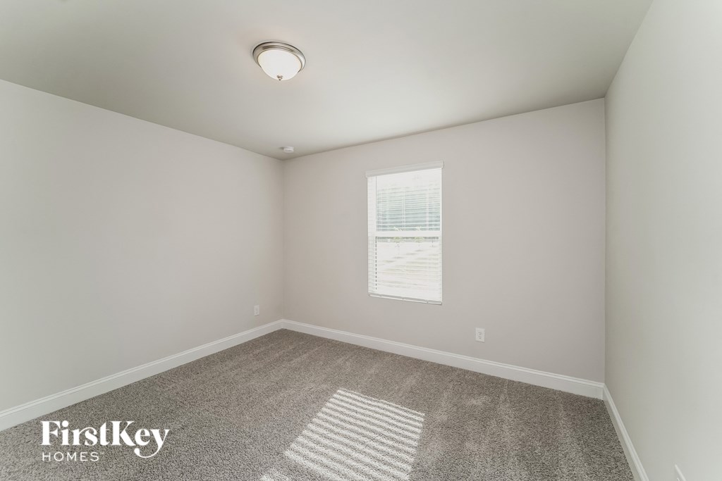 a bedroom with white walls and carpet and a window