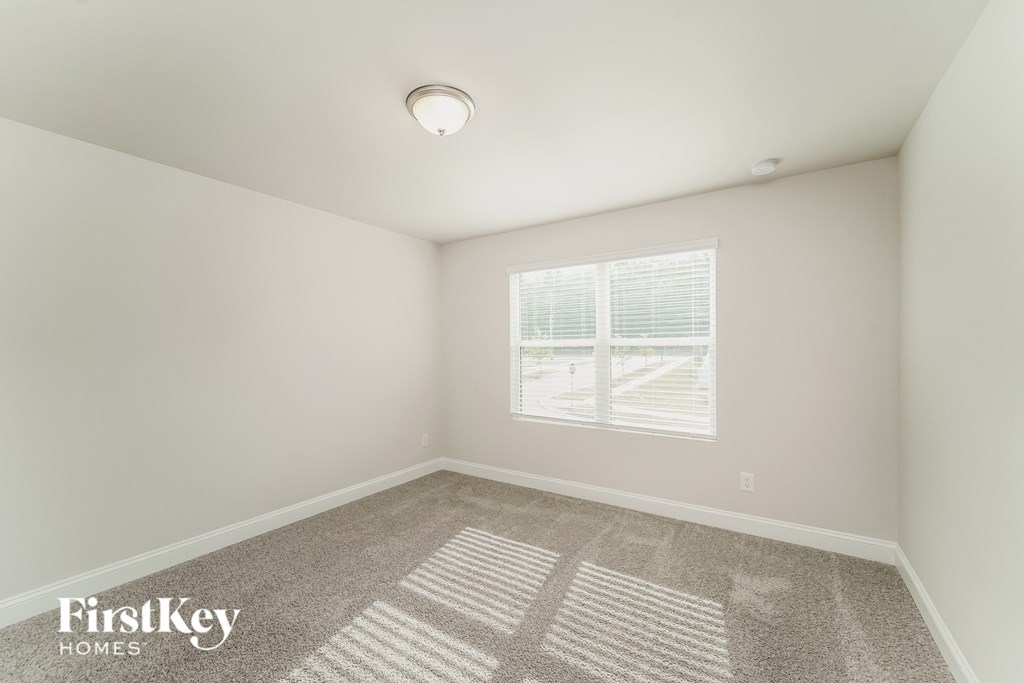 a bedroom with white walls and a window