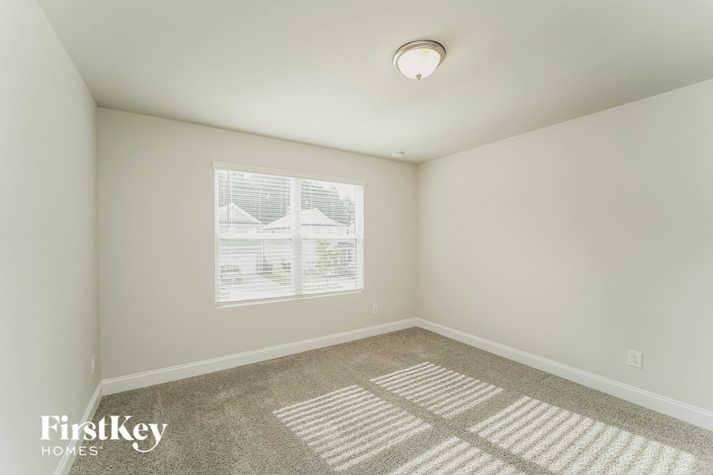 a bedroom with white walls and carpet and a window