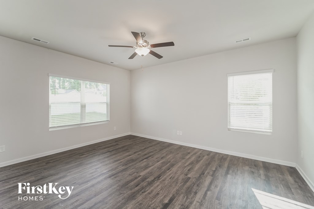 an empty living room with wood flooring and a ceiling fan
