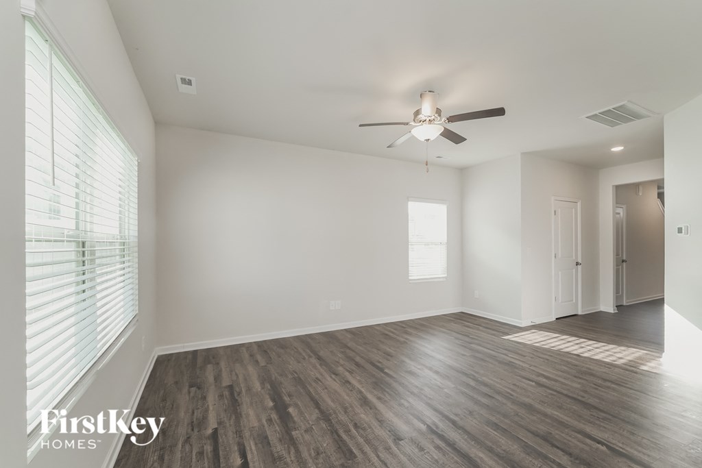 an empty living room with a ceiling fan and a large window
