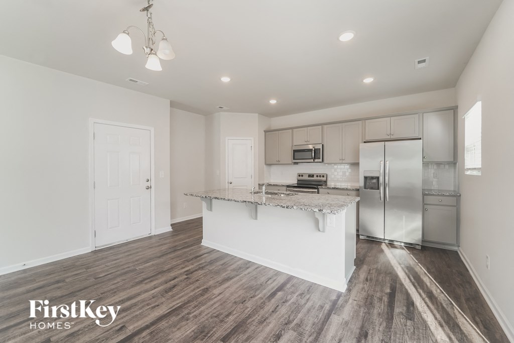 a white kitchen with a large island and stainless steel refrigerator