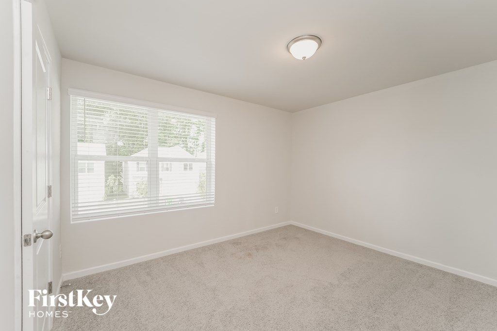 a bedroom with a large window and a carpeted floor