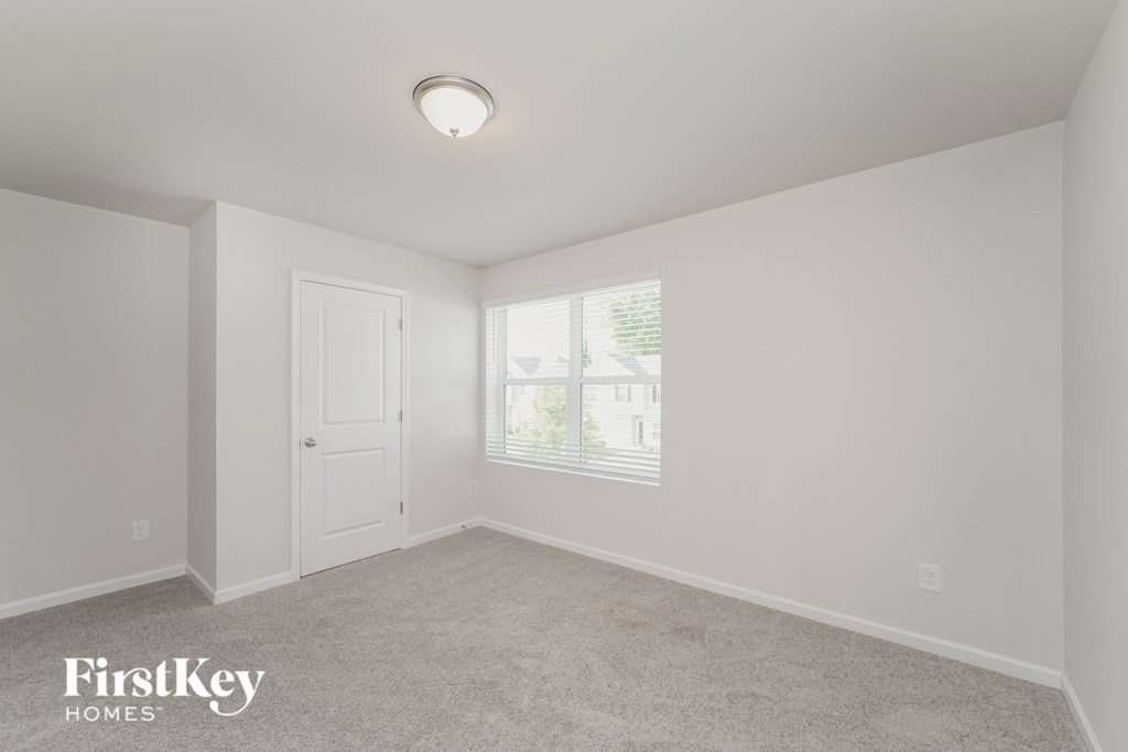 a bedroom with white walls and a white door and window