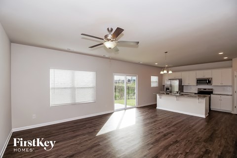 A spacious kitchen and living room with a ceiling fan and wooden floors.