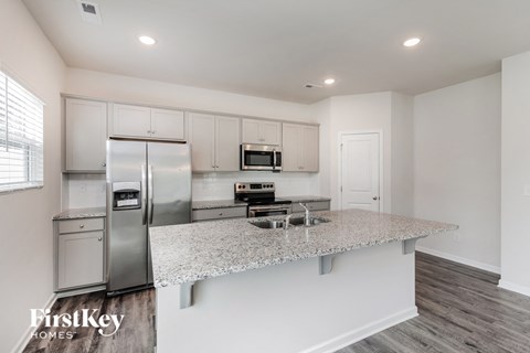 A kitchen with a refrigerator, microwave, and oven.