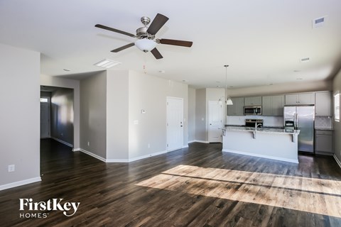 A spacious kitchen and living room with a wood floor and a ceiling fan.