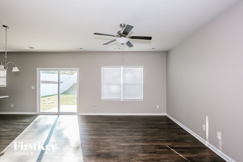 A spacious room with a ceiling fan and sliding glass doors leading to a view of the outdoors.