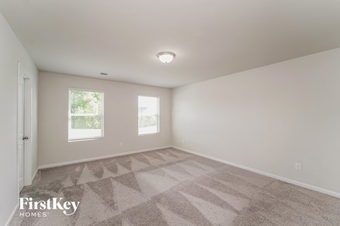 a spacious living room with carpet and two windows