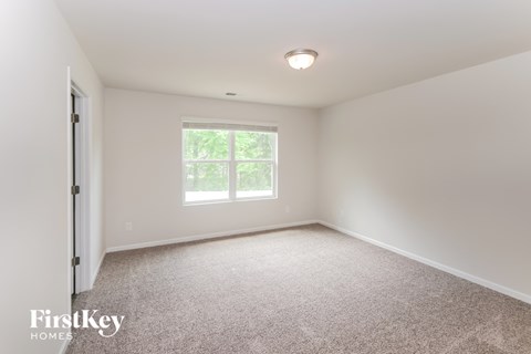 a bedroom with a large window and a carpeted floor