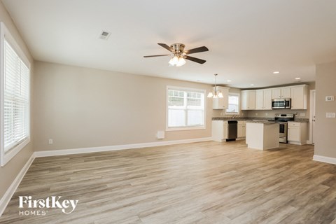 A spacious room with a ceiling fan and wooden flooring.