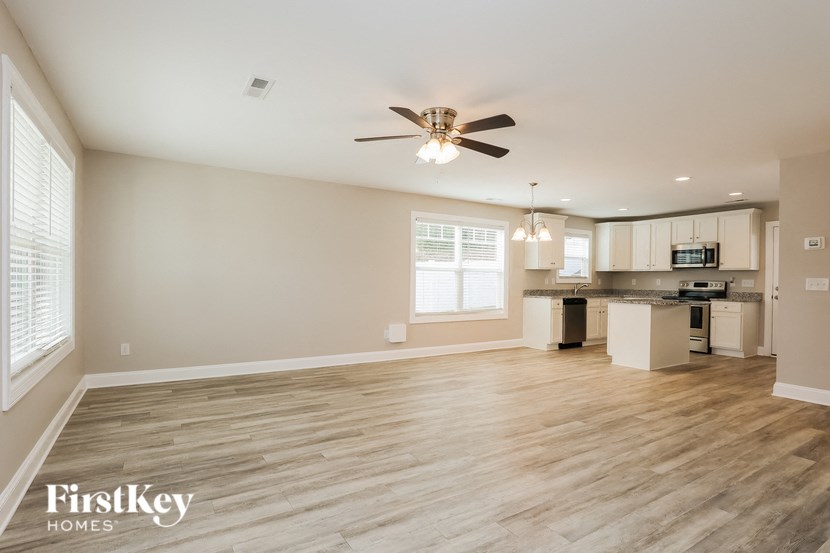 A spacious room with a ceiling fan and wooden flooring.
