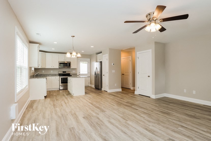 A spacious kitchen and living room with a ceiling fan and hardwood floors.