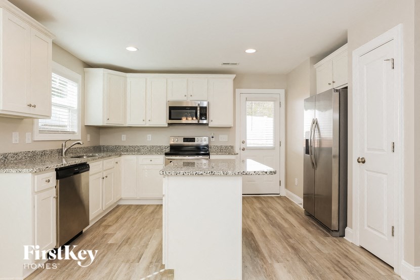 A kitchen with white cabinets and a wooden floor.