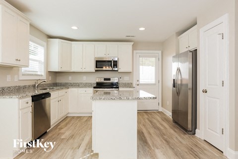 A kitchen with white cabinets and a wooden floor.