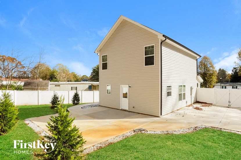 A house with a beige exterior and a white fence is for sale.