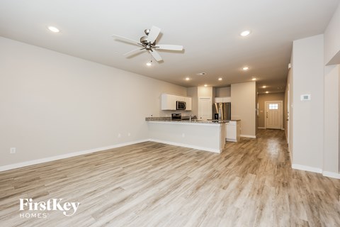 A spacious room with a kitchenette and wooden flooring.