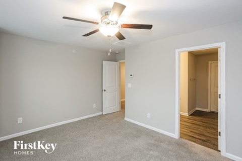 a bedroom with a ceiling fan and a door to a hallway
