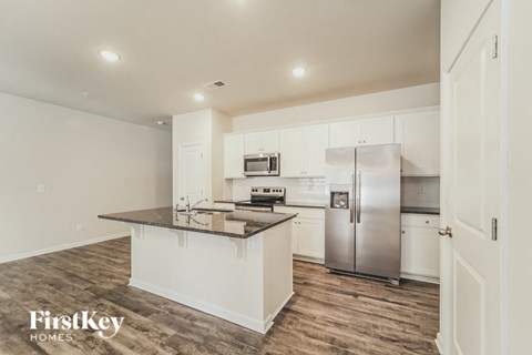 a white kitchen with an island and stainless steel refrigerator