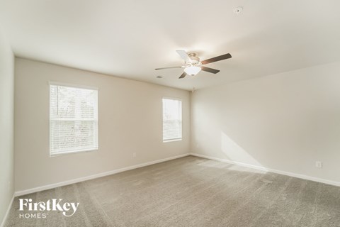 a spacious living room with carpet and a ceiling fan