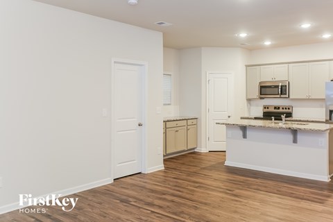 A kitchen with a white counter top and wooden floors.