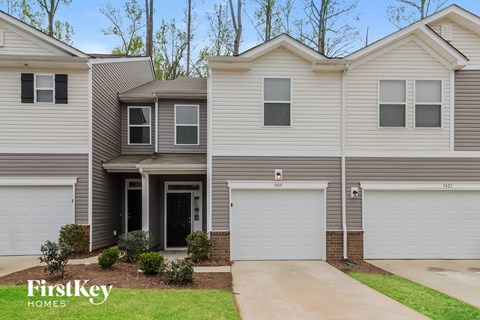 A row of houses with the first one being a two story house with a garage.