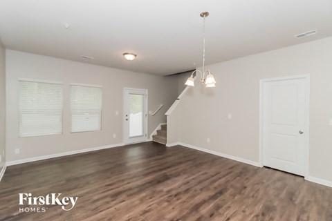 A spacious room with wooden floors and a staircase leading to another level.