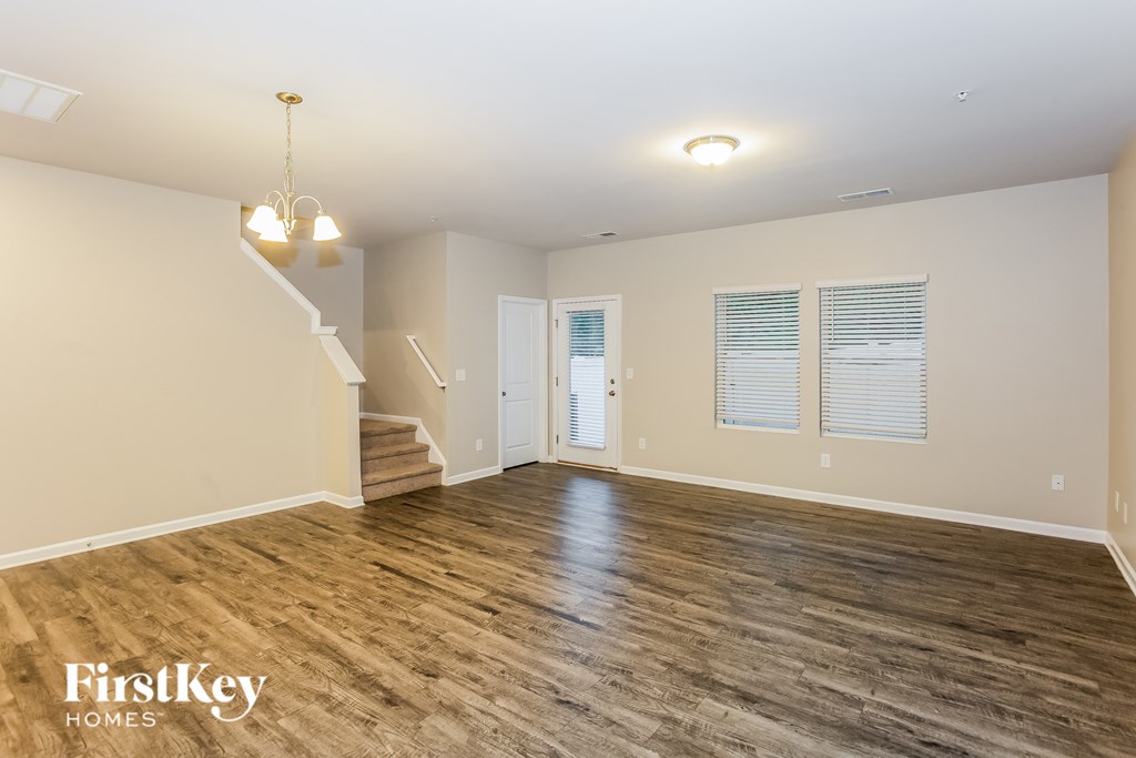 A spacious room with wooden flooring and a staircase leading to another level.