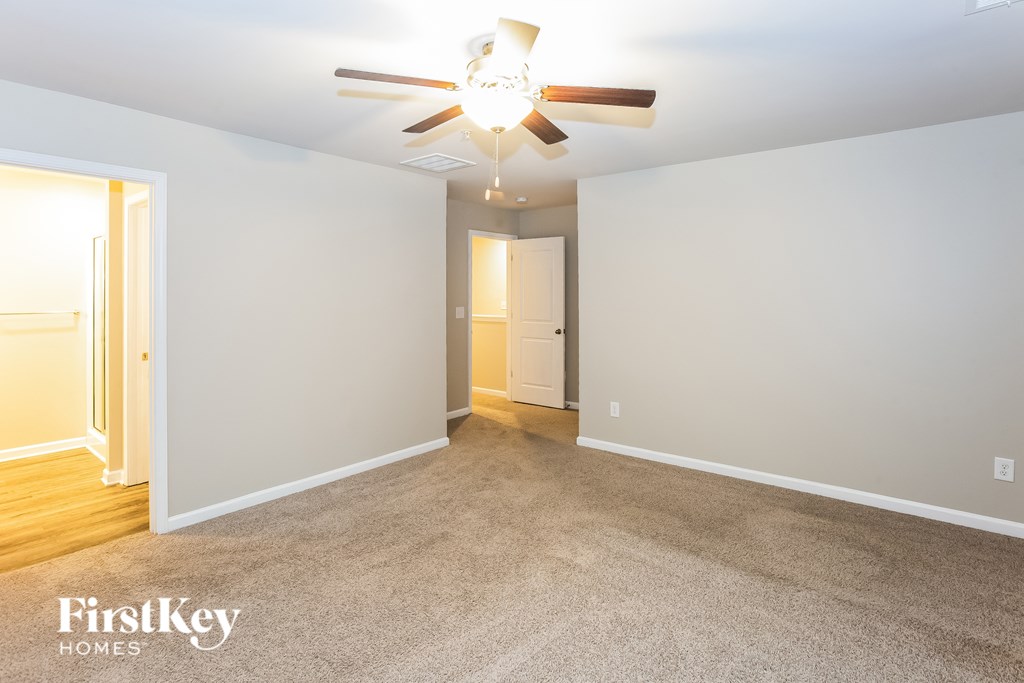 A spacious room with a ceiling fan and carpeted floor.