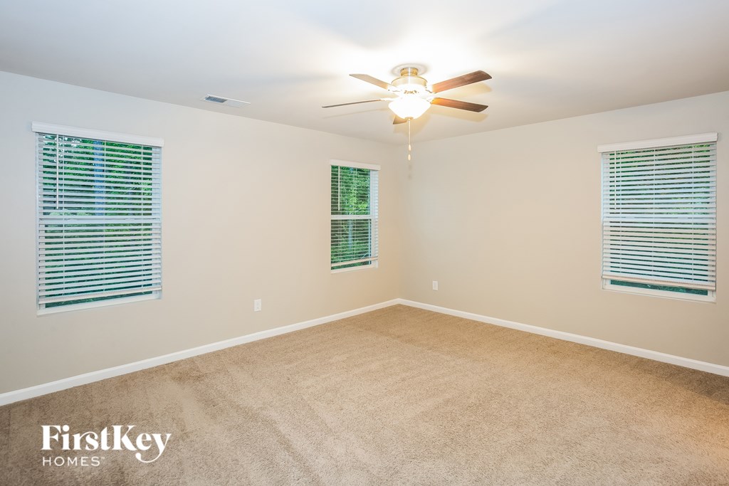 A room with a ceiling fan and two windows with blinds.