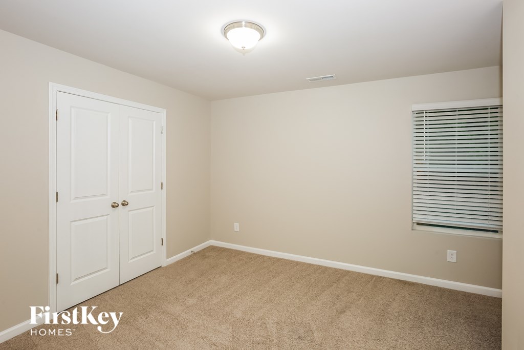 A room with a white door and a window with blinds.
