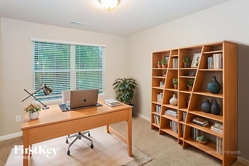 A room with a desk, laptop, and a bookshelf.