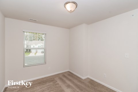 a bedroom with white walls and a window