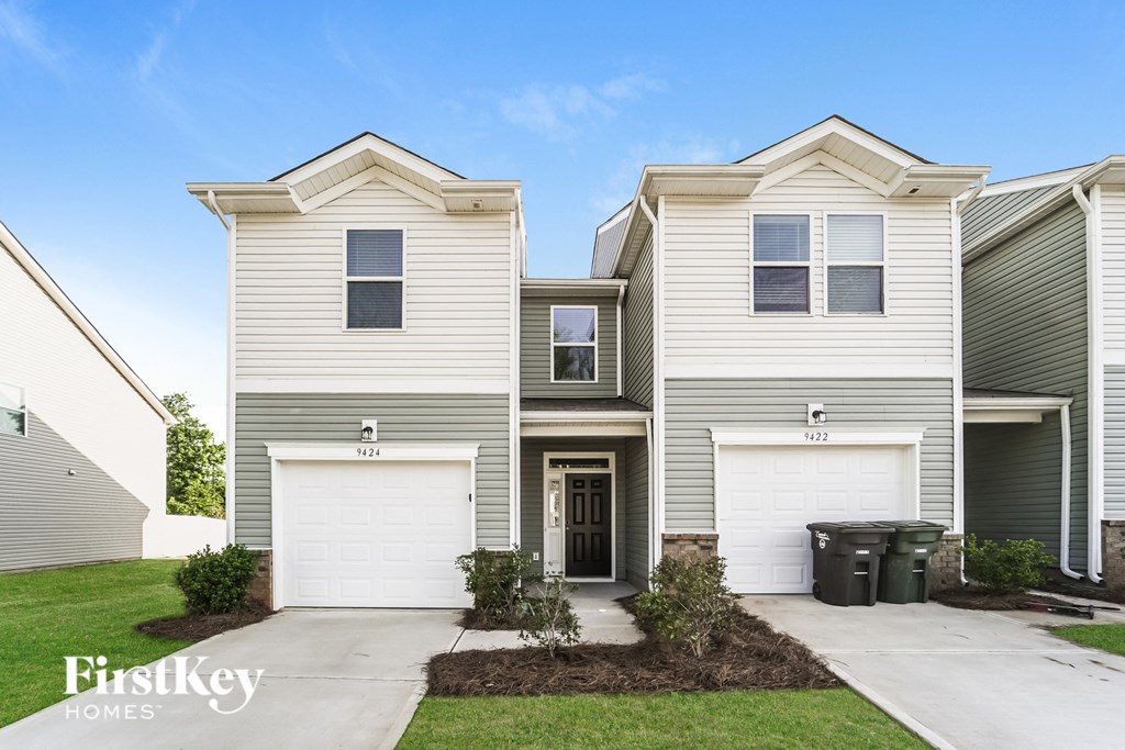 a white and gray house with two garage doors and a sidewalk