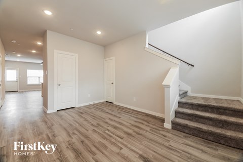 A spacious room with wooden flooring and a staircase leading to another level.