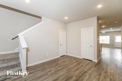 A spacious room with wooden floors and a staircase leading to the upper level.