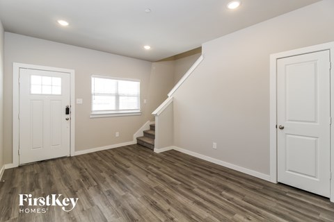 A spacious room with wooden flooring and a staircase leading to another level.