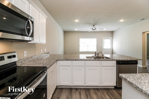 A kitchen with white cabinets and a granite countertop.