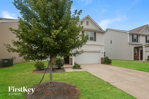 A tree in a brown circle of dirt stands in front of a house.