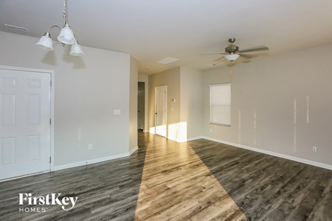 A spacious room with wooden flooring and a ceiling fan.