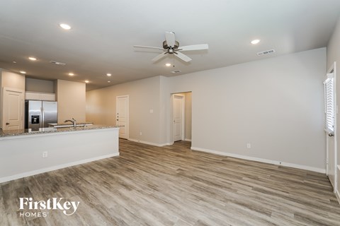 A spacious room with a fan and light wood flooring.