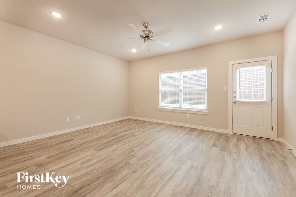 the spacious living room with hardwood floors and a ceiling fan