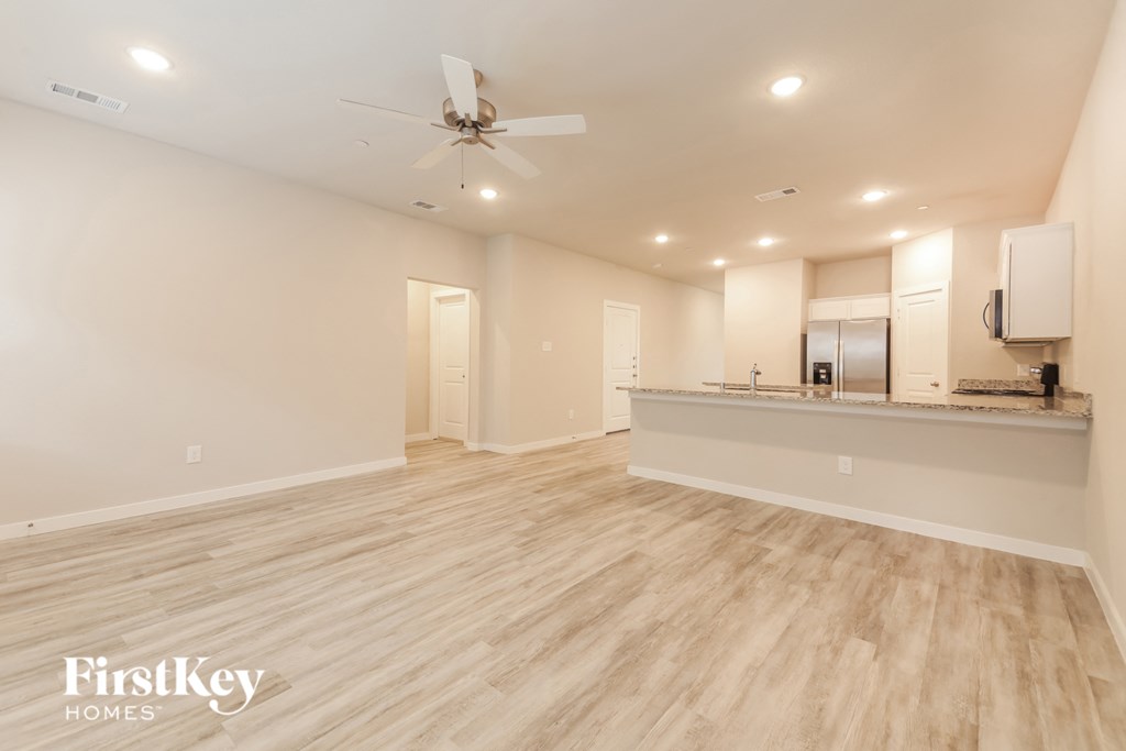 a living room with a kitchen and a ceiling fan