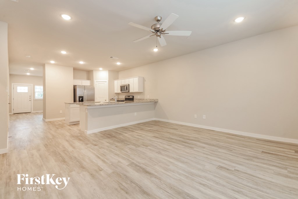 a living room with a kitchen and a ceiling fan