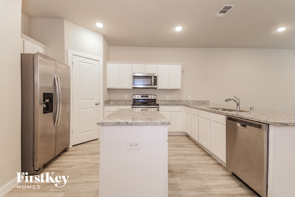 a white kitchen with stainless steel appliances and granite counter tops
