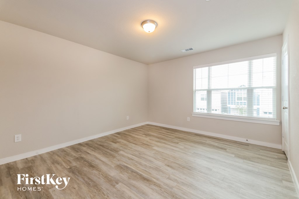 the spacious living room with wood flooring and a large window